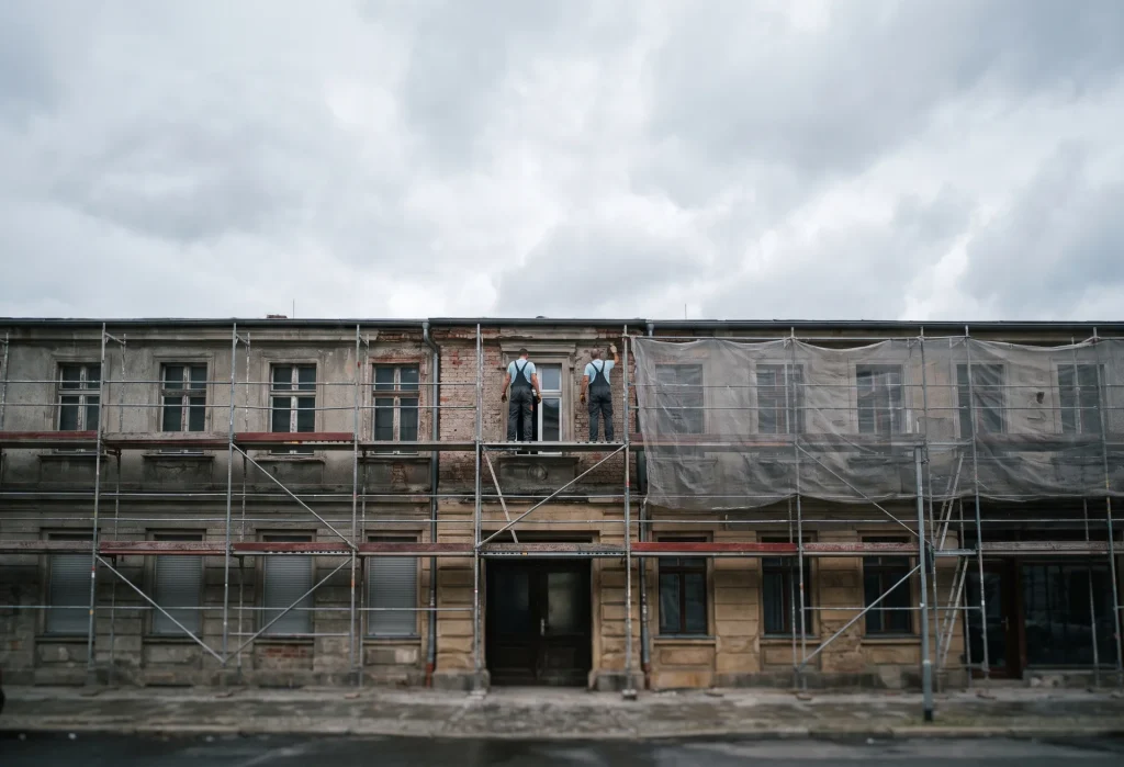 Sanierte Altbaufassade mit Gerüst, Bauarbeiter von East West Bau